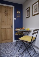 Cuisine-salle à manger avec chaises de bistrot et revêtement de sol à motifs.