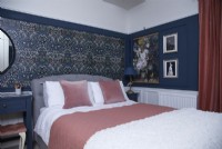 Chambre avec papier peint à motifs et murs et lambris bleu foncé.
