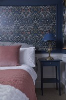Chambre avec papier peint à motifs et murs et lambris bleu foncé.