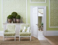 Chambre lambrissée classique verte avec chaises et vue sur le hall.