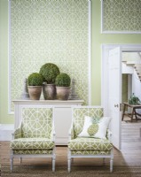Deux chaises à motifs verts devant un mur de panneaux recouverts de papier peint