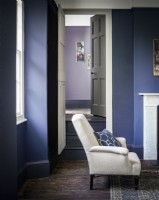 Salon peint en violet/bleu avec une chaise à partir de la porte