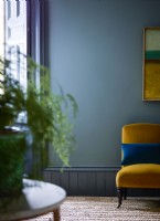 Mur peint en bleu avec chaise jaune et volets