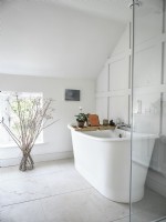 Baignoire sur pied blanche dans une salle de bains blanche classique avec mur lambrissé