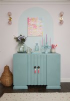 Salon montrant une armoire turquoise recyclée avec des détails muraux peints et une peinture abstraite.