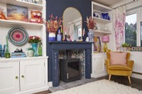 Salon avec cheminée, poêle à bois, alcôve de rangement et ornements et accessoires colorés.