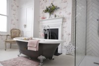 Salle de bain avec baignoire sur pieds, cheminée et papier peint flamant rose.