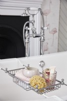 Détail de la baignoire à roulettes montrant un support de bain avec une éponge naturelle et des produits de beauté.