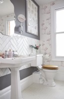 Salle de bain avec lavabo, carrelage blanc à chevrons et papier peint flamant rose.