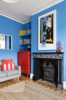 Poêle à bois et cheminée dans un salon bleu avec armoire et étagères en alcôve recyclées rouges