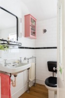 Salle de bain carrelée blanche et noire avec meuble mural rose