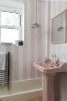 Salle de bain rétro avec lavabo rose et papier peint à rayures