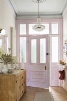 Porte d'entrée et lustre peints en rose dans un couloir de style vintage