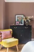 Armoire noire et chaise jaune dans la chambre aux murs peints en rose
