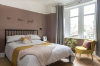 Chambre d'amis moderne avec mur peint en rose foncé et chaise jaune