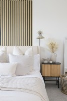 Détail d'une chambre moderne avec papier peint effet bois à lattes derrière la tête de lit