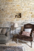 Fauteuil en velours marron en pays salon avec murs en pierres apparentes