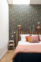 Palette en bois récupérée utilisée comme tête de lit dans une chambre éclectique