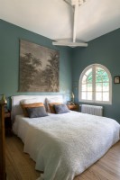 Fenêtre cintrée et murs peints en bleu sarcelle dans la chambre de campagne