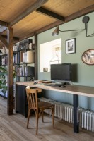 Long bureau contre un mur peint en vert