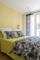 Chambre avec literie à motifs noir et blanc et murs jaunes