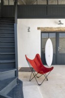 Chaise design et planche de surf au bas des escaliers dans le couloir moderne