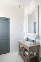 Meuble vasque en bois dans une salle de bain blanche moderne avec porte peinte en gris