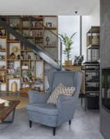 Un espace cosy avec un fauteuil au fond d'une bibliothèque avec des décorations et des escaliers
