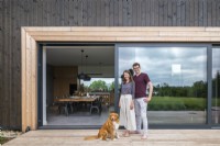 Les propriétaires de la maison avec le chien debout sur la terrasse dans le contexte de l'intérieur de la maison