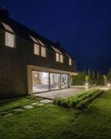 Vue nocturne du jardin à la maison avec des intérieurs illuminés