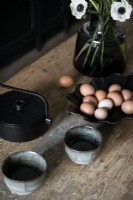 Oeufs dans un bol noir sur un plan de travail de cuisine en bois - détail