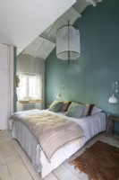 Mur peint en bleu sarcelle dans une chambre de campagne blanche