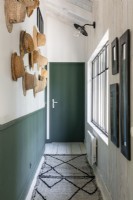 Couloir étroit avec boiseries peintes en vert et murs blancs