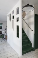 Escalier peint en vert et blanc avec un mur découpé inhabituel
