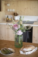 Détail de la nourriture sur une table en bois à côté d'un vase de fleurs sauvages