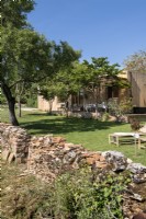 Mur de pierre rustique menant à un jardin de campagne avec des espaces de vie extérieurs