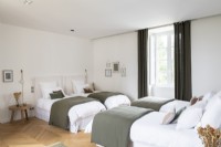 Chambre blanche et verte avec quatre lits