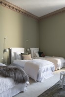 Trois lits simples dans une chambre aux murs peints en vert