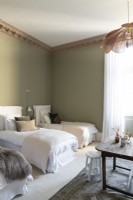Trois lits simples dans une chambre avec corniches en bois et murs verts