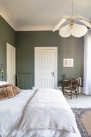 Chambre avec murs peints en vert et literie blanche