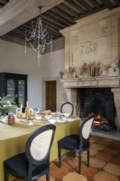Salle à manger classique avec feu allumé dans une grande cheminée en pierre
