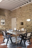 Table et chaises en bois dans la salle à manger de pays avec des murs en pierre