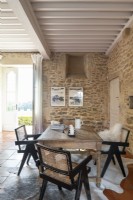 Table en bois dans un salon de campagne aux murs en pierres apparentes