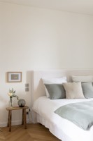 Chambre blanche simple avec coussins et couvre-lit gris pâle