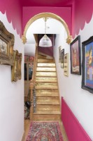 Un escalier peint en or dans un couloir peint en rose et blanc festonné