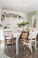 Table à manger en plan ouvert cuisine-salle à manger rose pâle et vert avec mélange éclectique de chaises en bois