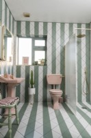 Salle de bains carrelée à rayures vertes et blanches avec sanitaires roses