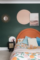 Tête de lit orange contre un mur vert foncé