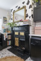 Ancienne cheminée victorienne et gamme peinte en noir et or dans une cuisine monochrome
