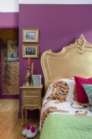 Lit français peint en or et table d'appoint dans une chambre rose
